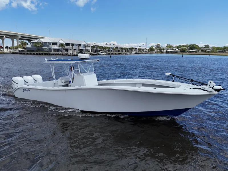 Slide: The Image of 2003 Yellowfin 36 Offshore boat cruising on a calm river under a clear blue sky. - 0