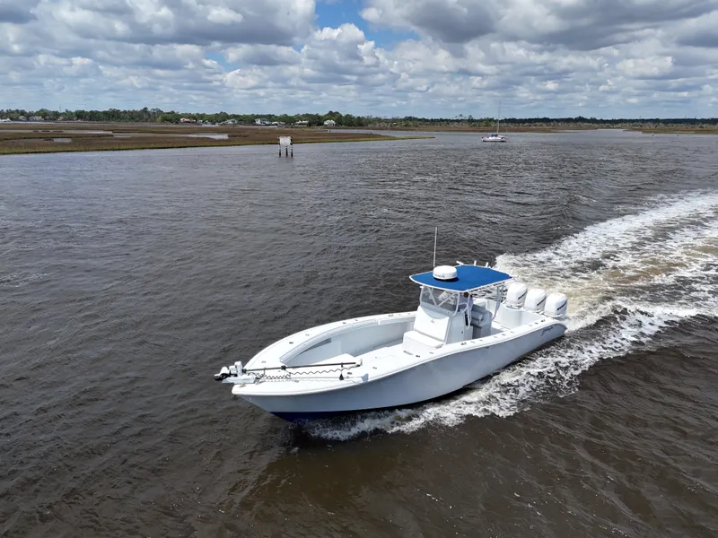 Slide: The Image of 2003 Yellowfin 36 Offshore boat cruising on a river under a cloudy sky. - 12