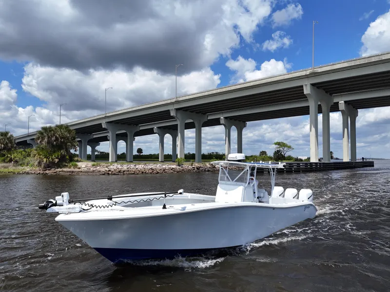Slide: The Image of 2003 Yellowfin 36 Offshore boat cruising under a bridge on a sunny day. - 13