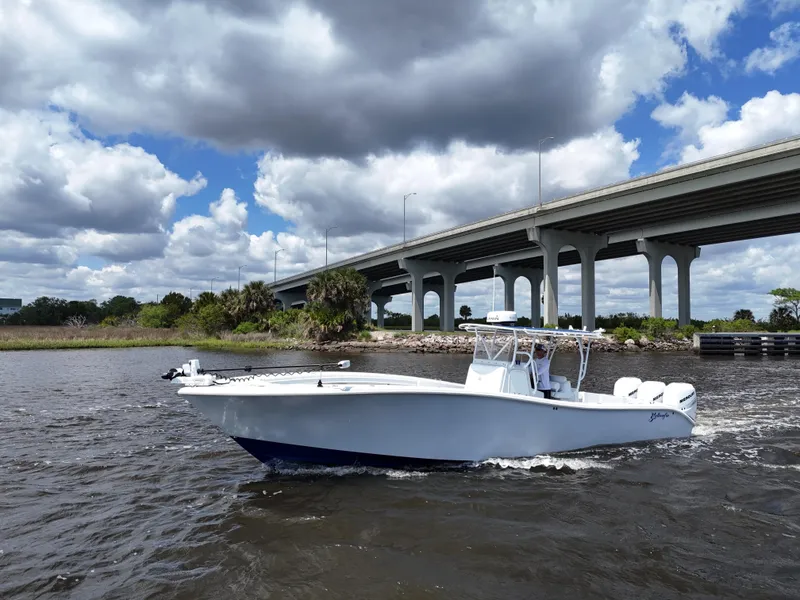 Slide: The Image of 2003 Yellowfin 36 Offshore boat cruising under a cloudy sky near a bridge. - 14