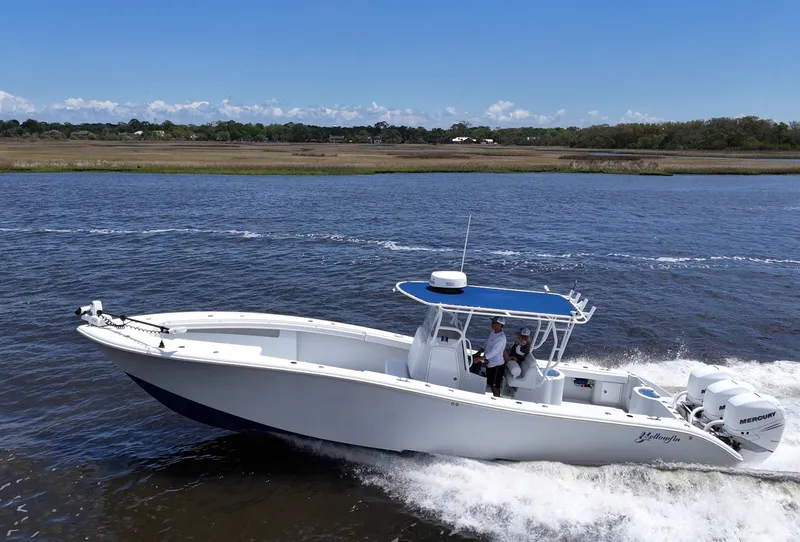 Slide: The Image of 2003 Yellowfin 36 Offshore boat cruising on a river under a clear blue sky. - 15