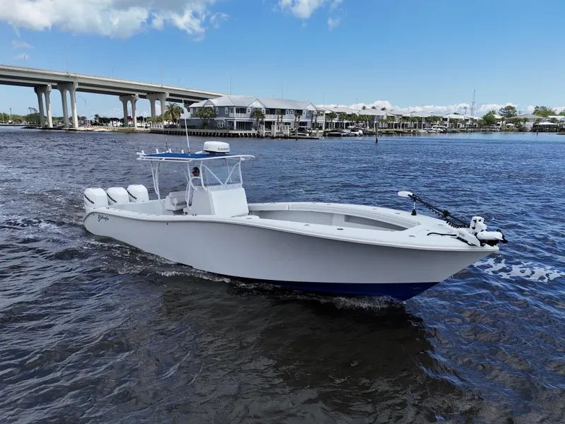 Slide: The Image of 2003 Yellowfin 36 Offshore boat cruising on a river near a bridge and waterfront homes. - 16