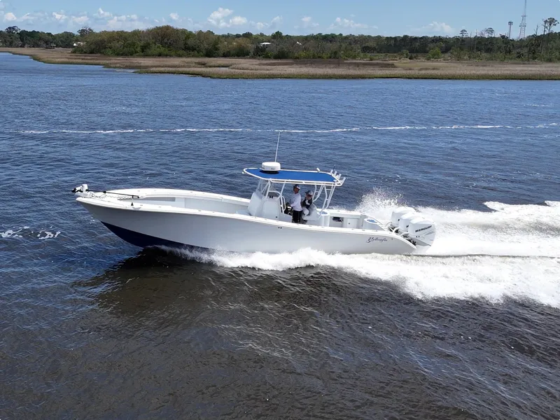 Slide: The Image of 2003 Yellowfin 36 Offshore boat cruising on a calm river under a clear sky. - 17
