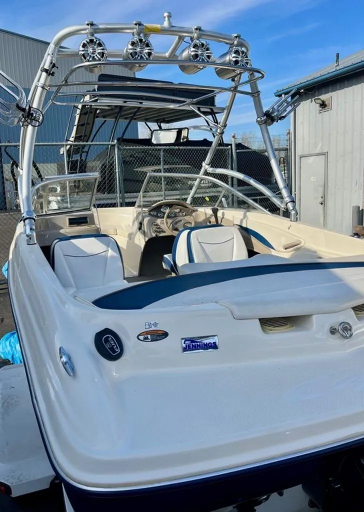 Slide: The Image of 2002 Bayliner 185 boat with wakeboard tower and speakers, docked near a building. - 2