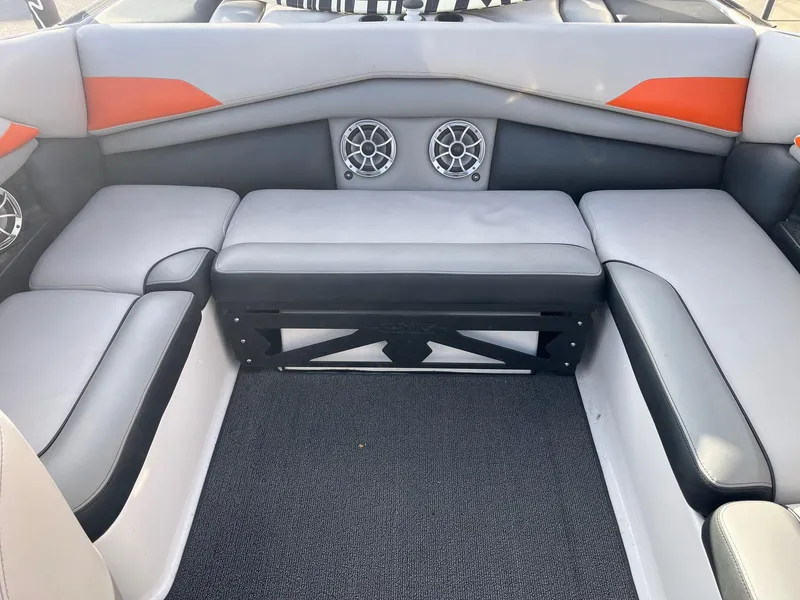 Slide: The Image of 2016 Axis Boats A22 interior seating with gray and orange upholstery, featuring built-in speakers. - 17
