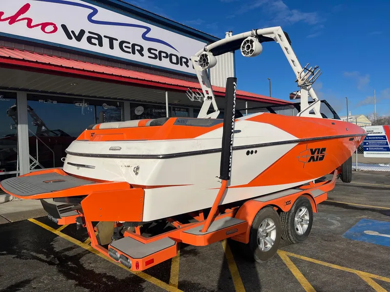 Slide: The Image of 2016 Axis Boats A22 in orange and white, parked outside a water sports store. - 4