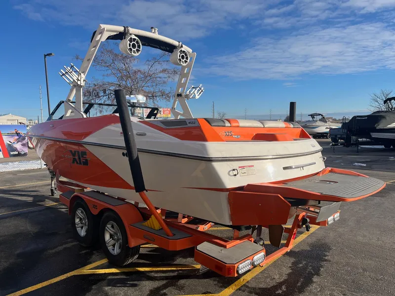 Slide: The Image of 2016 Axis Boats A22 in orange and white, parked on a trailer under a clear sky. - 7