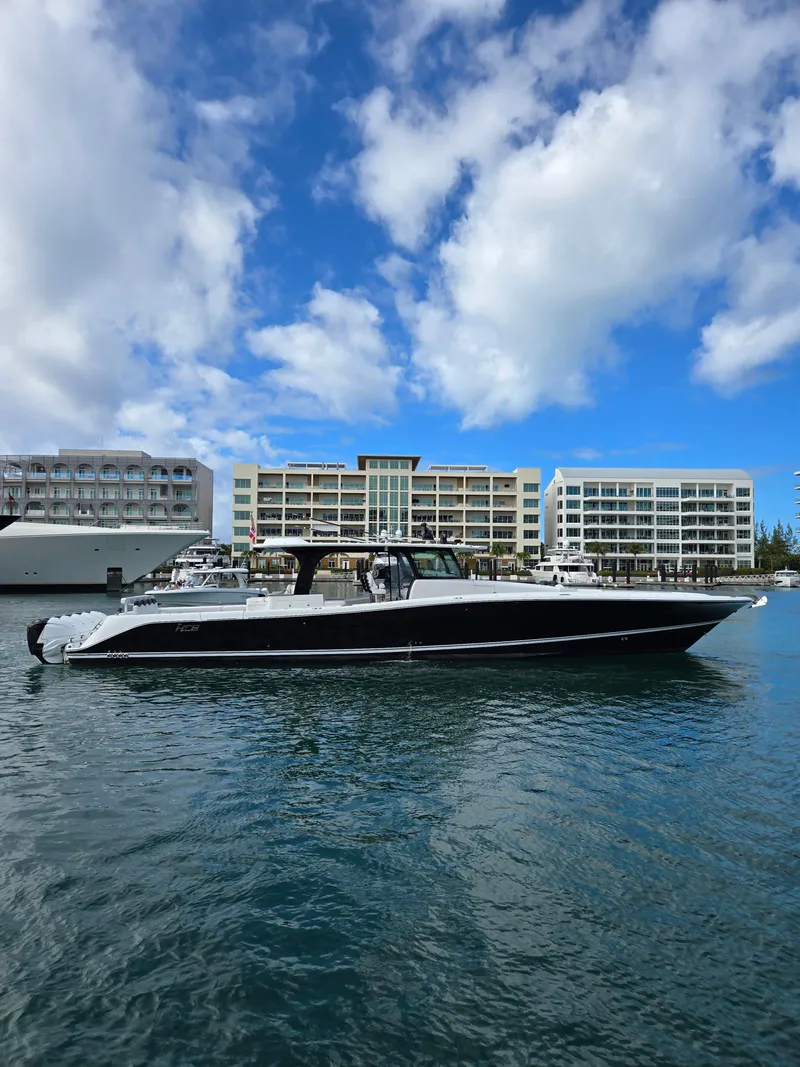 Slide: The Image of 2021 HCB 65 Estrella yacht docked in marina, modern buildings in background, blue sky. - 1