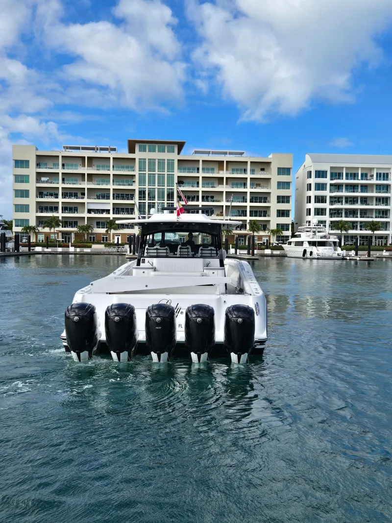 Slide: The Image of 2021 HCB 65 Estrella boat with six engines in a marina, modern buildings in background. - 14