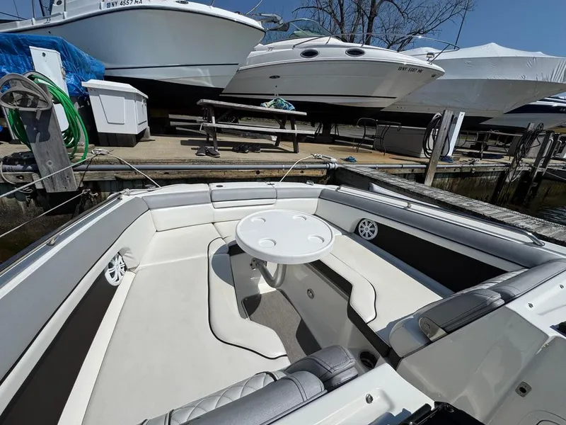 Slide: The Image of 2016 Sea Ray SDX 270 boat interior with seating and table, docked near other boats. - 14