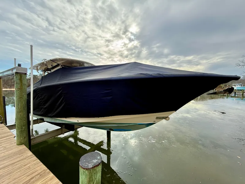 Slide: The Image of 2016 Scout 350 LXF boat covered and docked on a lift under cloudy skies. - 11