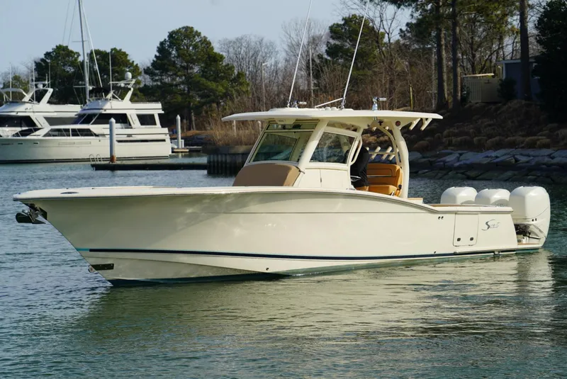 Slide: The Image of 2016 Scout 350 LXF boat on calm water, with trees and yachts in the background. - 17