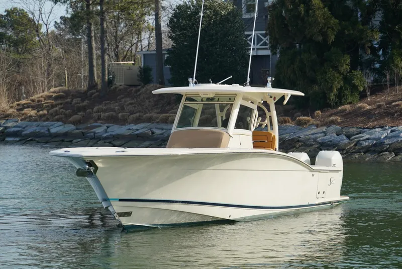Slide: The Image of 2016 Scout 350 LXF boat on calm water near a rocky shoreline. - 20