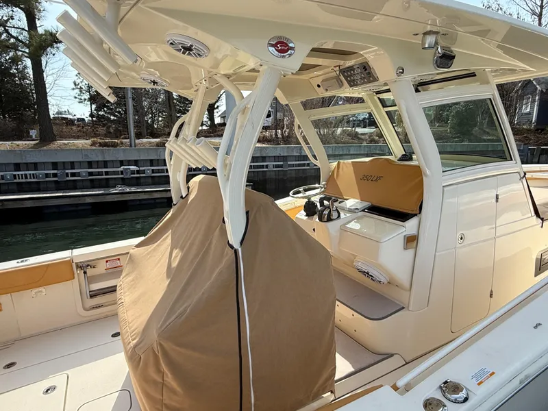 Slide: The Image of 2016 Scout 350 LXF boat interior with covered seats and helm, docked by the water. - 22