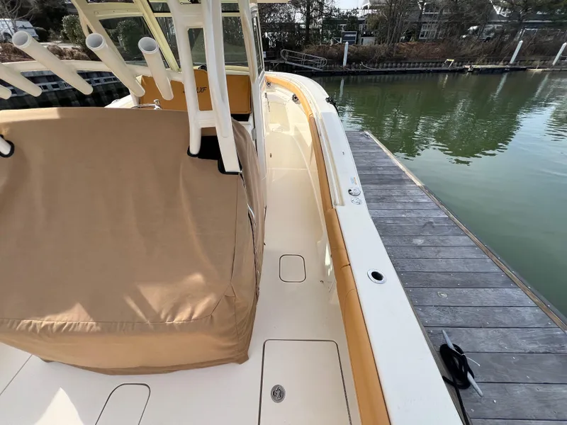 Slide: The Image of 2016 Scout 350 LXF boat docked, featuring beige seating and rod holders. - 30