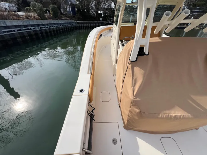 Slide: The Image of 2016 Scout 350 LXF boat docked, featuring covered seating and rod holders. - 31