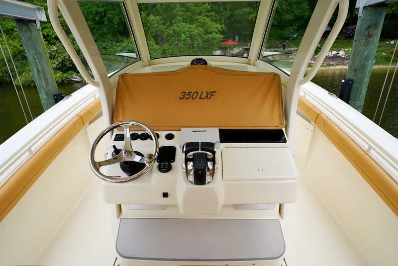 Slide: The Image of 2016 Scout 350 LXF boat helm with steering wheel and controls, docked by lush greenery. - 4