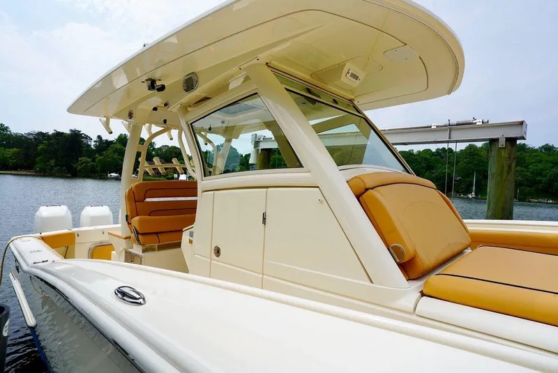 Slide: The Image of 2016 Scout 350 LXF boat with tan seating, docked on a calm lake. - 8