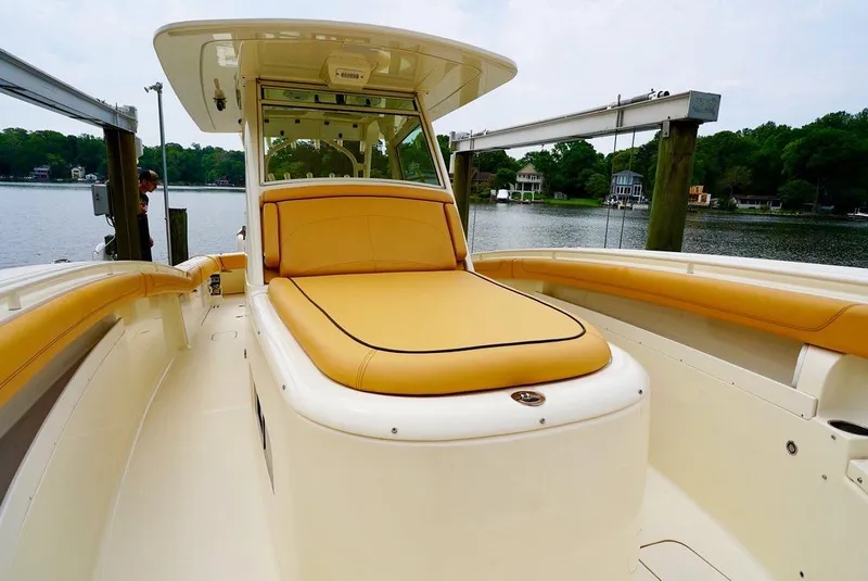 Slide: The Image of 2016 Scout 350 LXF boat with tan seating, docked by a serene waterfront. - 9