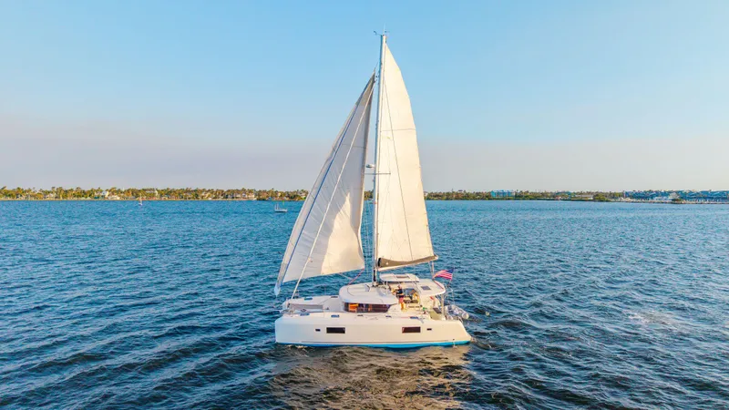 Slide: The Image of 2019 Lagoon 42 catamaran sailing on open water under clear blue skies. - 0