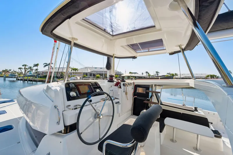 Slide: The Image of 2019 Lagoon 42 yacht cockpit with steering wheel, modern controls, and waterfront view. - 15