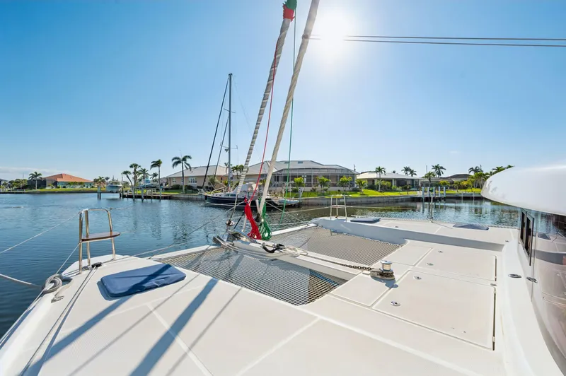 Slide: The Image of 2019 Lagoon 42 catamaran on sunny waterfront with palm trees and clear sky. - 21