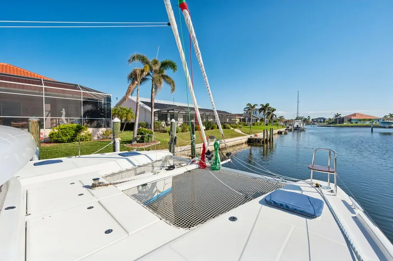 Slide: The Image of 2019 Lagoon 42 catamaran docked by a scenic waterfront with palm trees. - 28