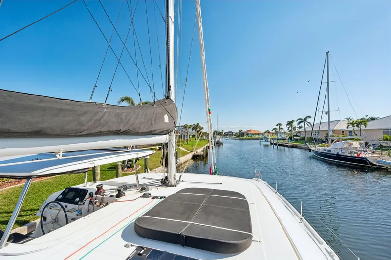 Slide: The Image of 2019 Lagoon 42 catamaran docked in a sunny marina, surrounded by palm trees and calm waters. - 33