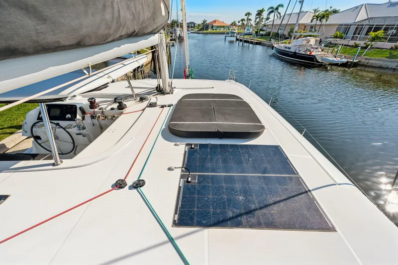 Slide: The Image of 2019 Lagoon 42 catamaran with solar panels docked in a scenic canal. - 34
