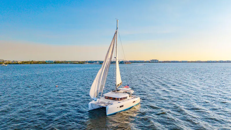 Slide: The Image of 2019 Lagoon 42 catamaran sailing on open water at sunset. - 6