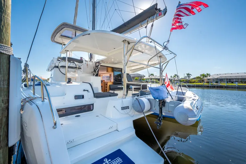 Slide: The Image of 2019 Lagoon 42 catamaran docked, featuring spacious deck and flags, under clear blue sky. - 8
