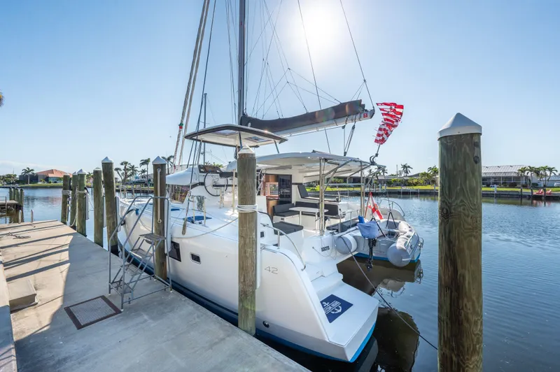 Slide: The Image of 2019 Lagoon 42 catamaran docked in a sunny marina setting. - 9