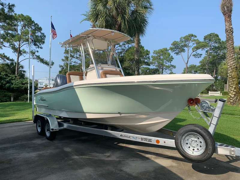 Slide: The Image of 2025 Pioneer 202 Islander boat on trailer, surrounded by trees and flags. - 0