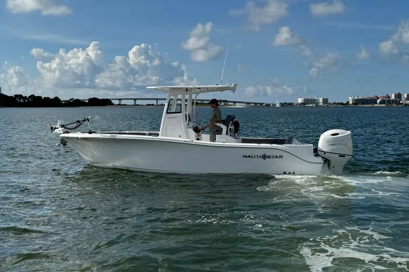 The Image of 2025 NauticStar 252 Legacy boat cruising on a sunny day with scenic waterfront views. - 1
