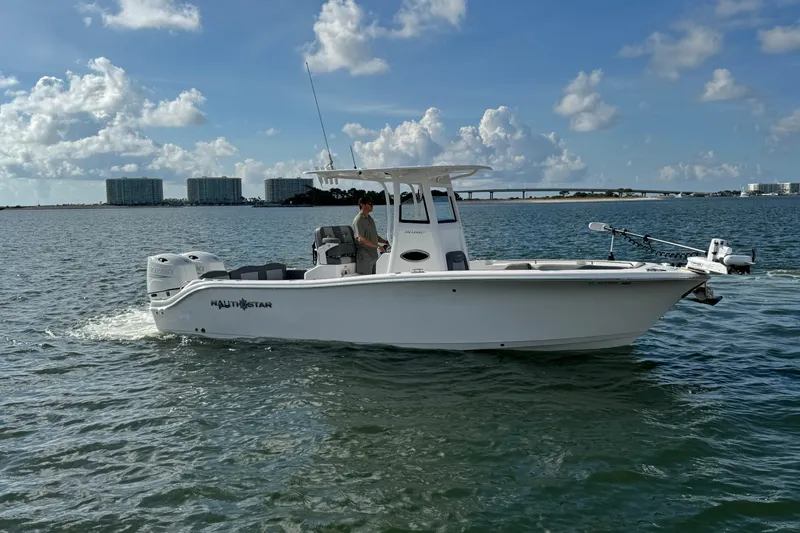 Slide: The Image of 2025 NauticStar 252 Legacy boat cruising on a sunny day with cityscape background. - 12