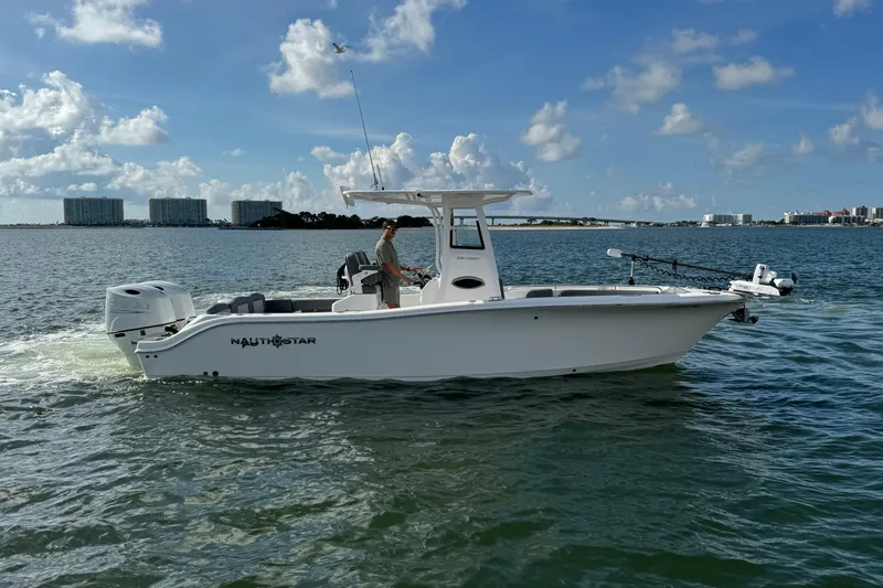 Slide: The Image of 2025 NauticStar 252 Legacy boat cruising on a sunny day with city skyline in background. - 13
