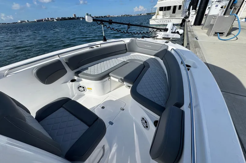 Slide: The Image of 2025 NauticStar 252 Legacy boat interior with cushioned seating, docked by the water. - 20