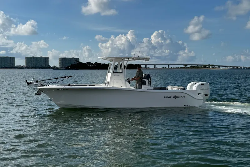 Slide: The Image of 2025 NauticStar 252 Legacy boat cruising on a sunny day with cityscape background. - 3