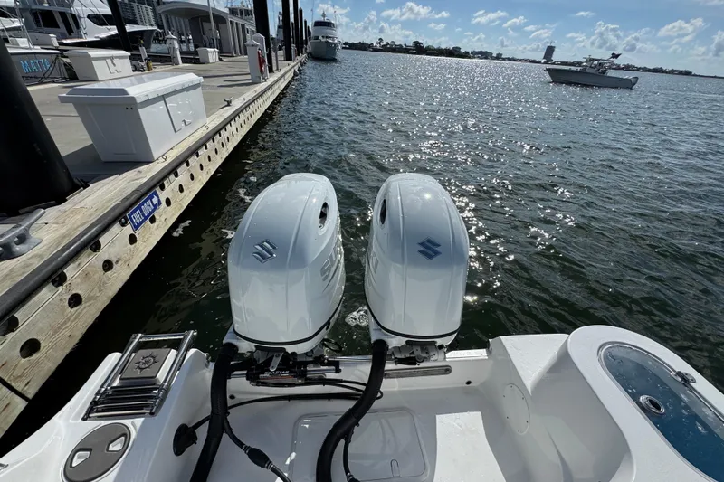 Slide: The Image of 2025 NauticStar 252 Legacy boat with dual outboard engines docked by the water. - 32