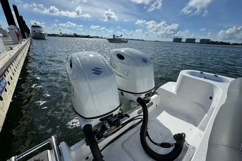 Slide: The Image of 2025 NauticStar 252 Legacy with dual Suzuki outboard motors docked by the water. - 34