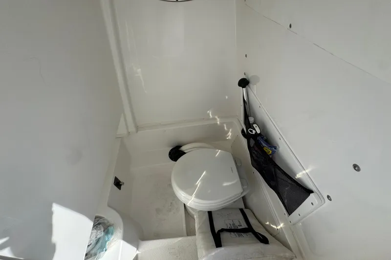 Slide: The Image of 2025 NauticStar 252 Legacy boat interior with compact marine toilet and storage. - 35