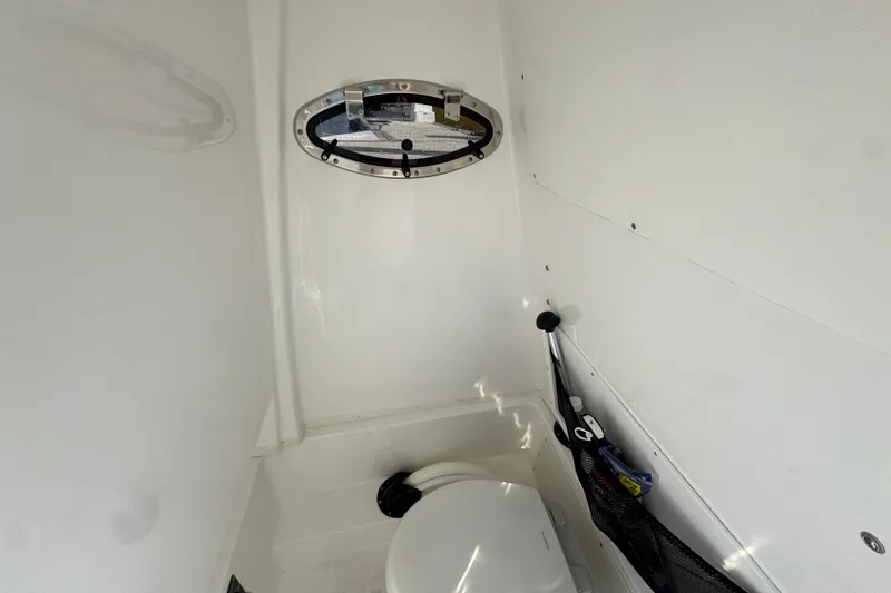 Slide: The Image of 2025 NauticStar 252 Legacy boat interior with compact marine toilet and porthole. - 36