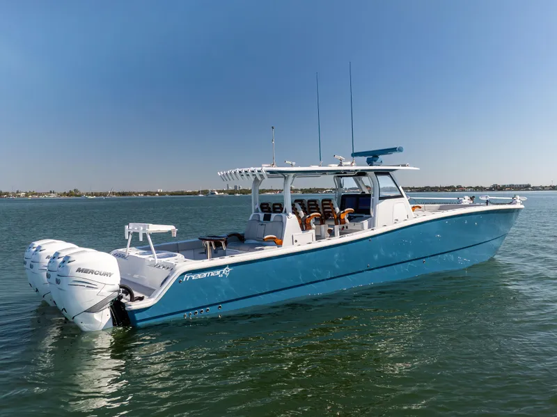 Slide: The Image of 2022 Freeman 43 boat on water, blue hull, twin Mercury engines, clear sky. - 2