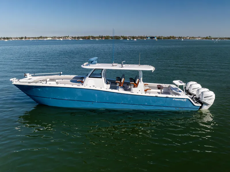 Slide: The Image of 2022 Freeman 43 boat on calm water, featuring a sleek blue design and multiple outboard engines. - 6