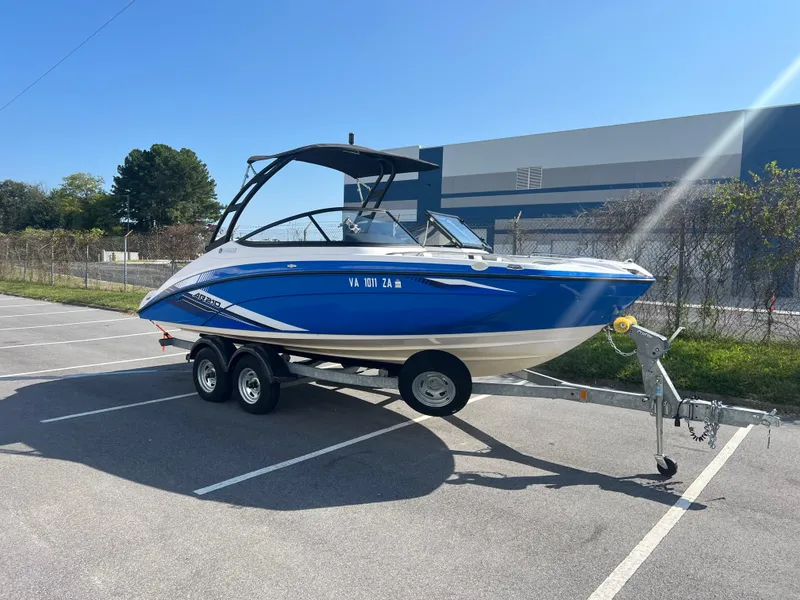 Slide: The Image of 2019 Yamaha Boats AR210 on trailer in parking lot, blue and white design. - 1
