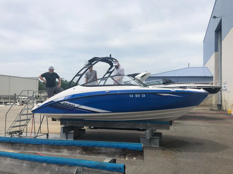 Slide: The Image of 2019 Yamaha AR210 boat on a stand with people inspecting it. - 3
