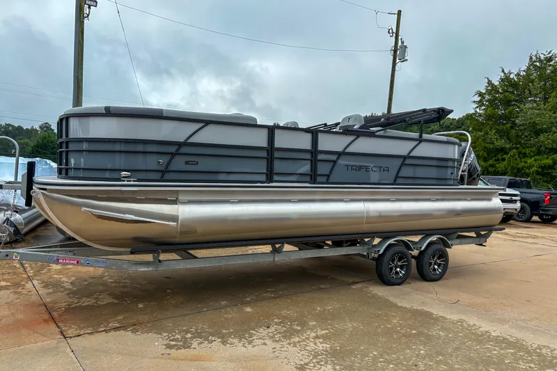 The Image of 2025 Trifecta 24 RF CS pontoon boat on trailer, parked outdoors. - 2