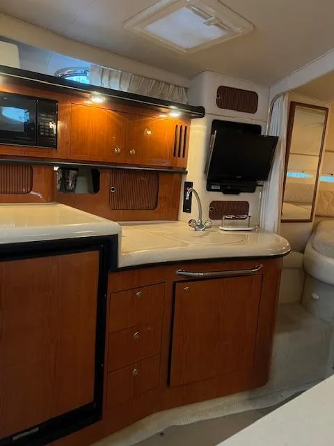 Slide: The Image of Interior of a 2002 Sea Ray Sundancer yacht, featuring a compact kitchen and modern amenities. - 15