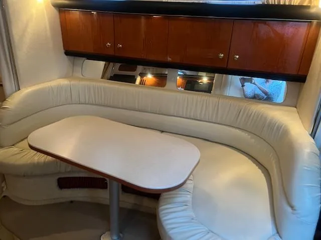 Slide: The Image of 2002 Sea Ray Sundancer interior with curved seating and wooden cabinets. - 19