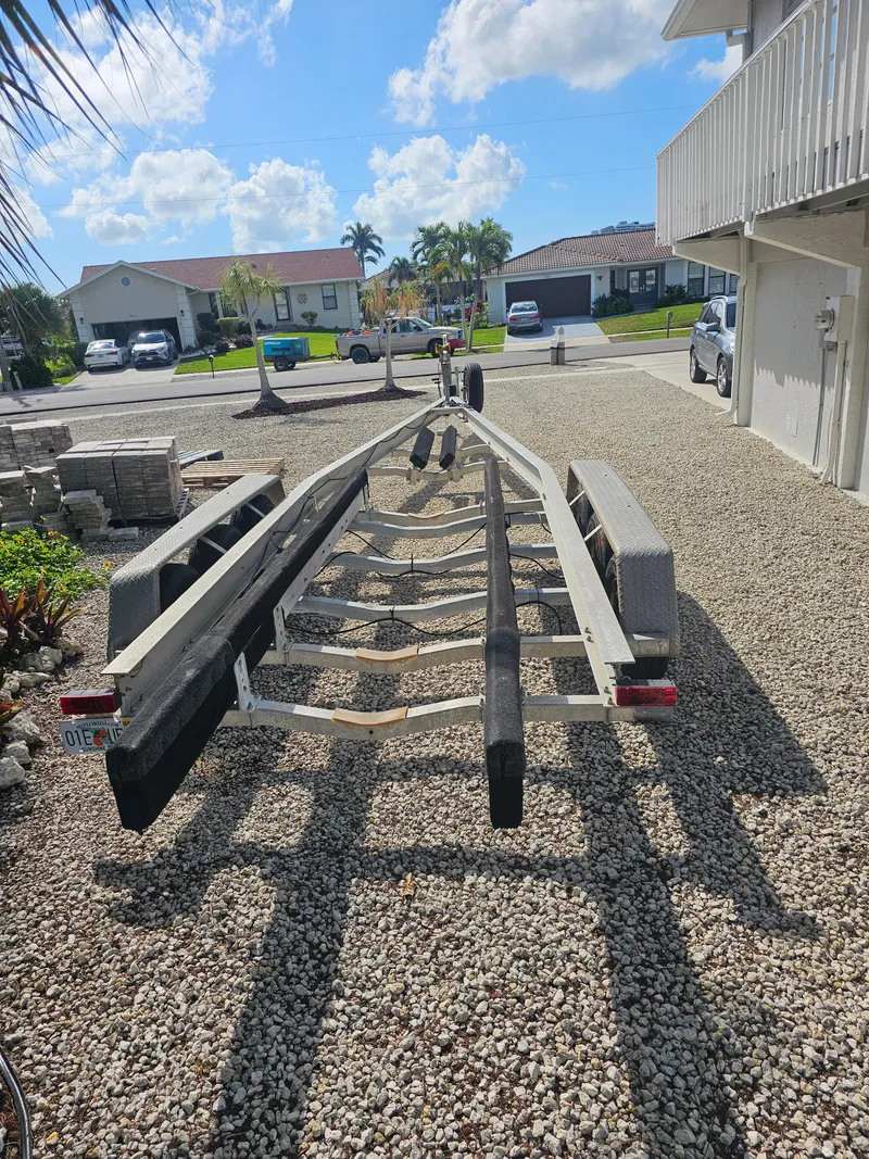 Slide: The Image of Empty boat trailer parked on gravel driveway, sunny day, residential neighborhood. - 12